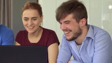 Çekici genç profesyonelleri, iki yakışıklı adamı ve neşeli kızıl saçlı kadını bir dizüstü bilgisayara gülerken gösteren canlı bir sahne. Ekranda eğlenceli bir şeyle karşılaştıklarında yoldaşlıkları parlıyor ve canlı bir atmosfer yaratıyorlar.