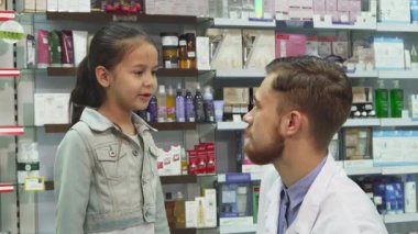 Renkli ürünlerle dolu parlak bir eczanede neşeli bir eczacı elinde küçük bir ilaç tüpü olan küçük bir kızla takılıyor. Sıcacık tokalaşmaları, annesinin bakışıyla pozitif enerji yayıyor. Yürek ısıtan bir ilgi anı yaratıyor.