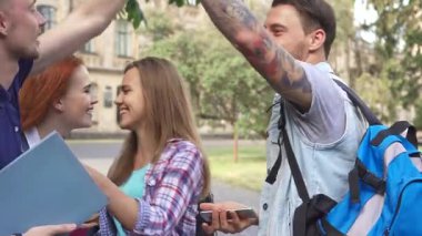 Çekici beyaz öğrencilerin kampüste güneşli bir günün tadını çıkarması, beşlik çakarken kahkahalarla gülmeleri ve akıllı telefondaki görüntülere hayran olmaları. Bu canlı sahne, arkadaşlığın ve gençlik enerjisinin özünü renkli bir şekilde yakalıyor.