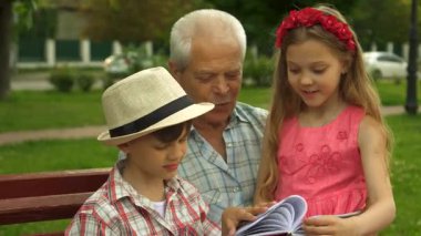 Büyüleyici beyaz çocuklar renkli bir kitaba dalmış dedeleriyle güzel bir anı paylaşıyorlar. Yakışıklı son sınıf öğrencisi yemyeşil bir bankta oturuyor. Pembe elbiseli ve şık görünümlü güzel torunu gibi.