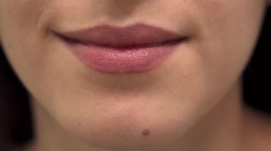 Parlak esmer bir kadın spaya büyüleyici bir gülümseme sergiliyor, kusursuz dişlerini ve yumuşak pembe dudaklarını sergiliyor. Bu yakın çekim onun parlayan cildini ve kendine bakmanın ve güzelliğin sakin atmosferini vurguluyor.