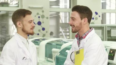 Parlak, yüksek teknolojili bir laboratuvarda, iki genç teknisyen neşeli bir sohbeti paylaşıyor, gülümsemeleri coşku saçıyor. Kıtır laboratuvar önlüğü ve lateks eldiven giyerek bilim dünyasında işbirliği ve keşif ruhunu somutlaştırıyorlar.