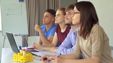Canlı bir yan görüş, modern ofis ortamında sevinçle alkışlayan bir grup beyaz yöneticiyi yakalıyor. İki şık erkek ve iki zarif kadın, canlı ofis dekorlarıyla çevrili şık bir masada oturmuş, başarılı bir sunumu kutluyorlar.