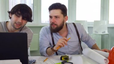 İki yetenekli Kafkasyalı mimar bir dizüstü bilgisayarı incelerken dinamik bir tartışmaya girerler, ifadeleri konsantrasyon ve takım çalışmasını yansıtır. Yakışıklı sakallı mühendis ve şık iş arkadaşı, bir kalem ve ölçü ile donatılmışlar.