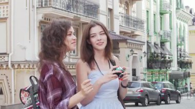 İki neşeli bayan arkadaş neşeyle canlı şehir manzarasının fotoğraflarını çekiyorlar, macera ve keşif ruhunu somutlaştırıyorlar. Şehir turunun güzelliğini kucakladıkça, kahkahaları havayı dolduruyor, birlikte unutulmaz anılar yaratıyorlar.