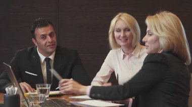 Gösterişli bir ofis ortamında, bir erkek ve iki kadın yeni iş projelerini tartışırken bir dizüstü bilgisayara odaklanıyorlar. Arkadaş canlısı tavırları ve profesyonel kıyafetleri ortak bir ruhu yansıtıyor, fikirleri ve stratejileri paylaştıkça