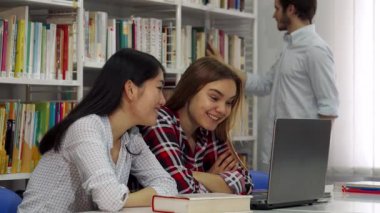 Parlak ve davetkar bir kütüphanede, iki odaklanmış kız ve yakışıklı sakallı bir adam dizüstü bilgisayarın üzerine eğilip, anlayış ve kahkahaları paylaşıyorlar. Üçlü yoldaşlık, bilgiyi birlikte keşfederken, ilham veren renkli kitaplıklarla çevrelenmiş olarak parlıyor.