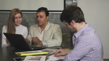 Dinamik bir ofis ortamında, yakışıklı genç bir işadamı enerjik iş diyagramlarını incelerken dikkatle not alıyor. Düşünceli tavrı takım çalışmasının enerjisini yansıtıyor, meslektaşları animasyon tartışmalarına girerken...