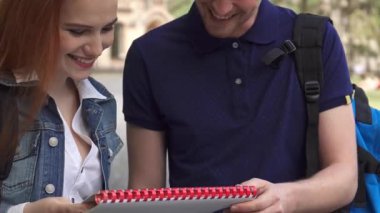 Çekici beyaz bir erkek öğrenci, canlı bir kampüsteki güzel kızıl saçlı sınıf arkadaşına defterindeki kavramları tutkuyla anlatıyor. Sahne, bereketli yeşillik ve güneşli bir günün sıcacık parıltısıyla çerçevelenmiş animasyon tartışmalarını yakalıyor.