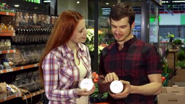 Çekici genç bir çift, hareketli bir süpermarkette alışveriş yaparken yiyecek kompozisyon etiketleri üzerine canlı bir tartışmaya girişiyor. Yakışıklı esmer adam ve güzel kızıl saçlı kız arkadaşı, ikisi de gündelik giyinmiş, konserve kutusunu gösteriyorlar.