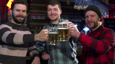 Üç neşeli arkadaş canlı bir barda buzlu bira bardaklarını kaldırarak arkadaşlığın ve kutlamanın özünü yakalıyorlar. Yakın çekimler, neşeli gülümsemelerini ve şık kıyafetlerini sergiliyor, kahkahalar ve güzel zamanlarla dolu sıcak bir atmosfer yaratıyor.