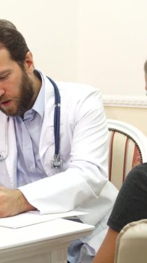 Parlak ve davetkar bir doktor ofisinde, kendini işine adamış beyaz önlüklü bir doktor, genç bir bayanla teşhisi tartışırken özenle notlar yazar. Anlamlı bir istişarede bulunduklarında atmosfer umut ve anlayış yayıyor.
