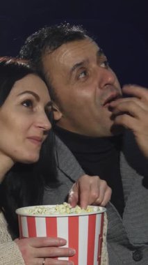 Hoş, olgun bir çift, loş bir sinemada sarılıp yatar, kahkahalarını ve patlamış mısırlarını paylaşır ve heyecan verici bir filme dalarlar. Işıl ışıl gülüşleri ve sevgi dolu bakışları sevgi ve neşe verici bir atmosfer yaratır.