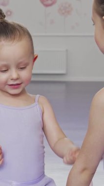 Canlı bir dans stüdyosunda, iki küçük sevimli balerin, bir tanesi ablasını eğlendirirken bir anlık saf neşe paylaşıyorlar. Onların bulaşıcı kahkahaları ve parlak gülümsemeleri mekanı aydınlatır, çocukluk arkadaşlığının özünü yakalar ve