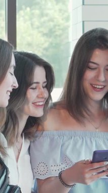 Üç hayat dolu genç kadın şık bir kahve dükkanında güzel bir şekilde selfie çekiyorlar. Kahkahaları güneş ışığında yankılanıyor. Sıcak bir atmosfer ve şık bir dekorla çevrili olarak dostluğu kutluyor ve unutulmaz anılar yaratıyorlar.