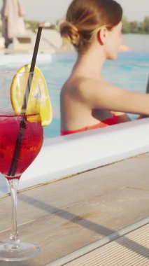 Canlı, etnik çeşitlilikte bir çift, pırıl pırıl bir yüzme havuzunda keyifli bir kaçışın tadını çıkarıyor, kahkahalarını ve tazeleyici kokteyllerini paylaşıyorlar. Sahne, limon dilimleriyle süslenmiş renkli içeceklerle renklendiriliyor. Tropikal bir ortamda yaz neşesi ve romantizmi yayıyor.