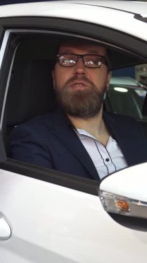 Şık giyimli, sakallı bir adam satış müdüründen arabanın anahtarlarını alırken heyecanla ışıldıyor ve canlı bir başarı ve tatmin ortamı yaratıyor. Bu canlı etkileşim, satıcıların profesyonelliğini vurguluyor.