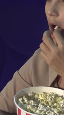 Büyüleyici bir yakın planda, uzun siyah saçlı genç bir kız çizgili bir patlamış mısır kutusu tutuyor, parmaklarıyla sessizce işaret veriyor. Işıl ışıl gözleri ve hevesli ifadesi film galasının heyecanını yakalıyor, rahat bir ortam yaratıyor.