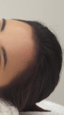 Kafkasyalı sakin bir kız, huzur dolu bir masaj masasının üzerinde uzanıyor. Yenilenme masajı yaparken gözleri yavaşça kapanıyor. Kabarık beyaz bir havlunun nazikçe kucaklaması başını sarar ve sakin bir spa atmosferi yaratır.