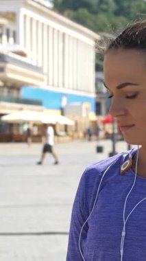 Parlak at kuyruklu odaklanmış genç bir kadın şık kulaklıklar takmış, canlı bir nehir yolunda saatini kontrol ediyor. Azimli bir bakışla, canlı bir şehir zeminine karşı enerji ve aciliyet saçan bir sürat koşusuna çıkıyor.