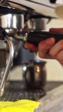 Kendini işine adamış genç bir adam, yetenekli bir barista, yeni demlenmiş bir espressoya ustaca şurup döker, odaklanmış elleriyle karışık kahve yapma sanatını sergiler. Kafenin sıcak, davetkar atmosferi kahvenin zengin aromasıyla güçlenir.