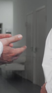 Gıcır gıcır beyaz laboratuvar önlüklü tanınmayan iki erkek doktor sıkı bir tokalaşma içinde, sağlık alanında güven ve işbirliğini simgeliyor. Bu dinamik an, hastane koridorunun gösterişli, verimsiz zeminine göre ruhu somutlaştırıyor.