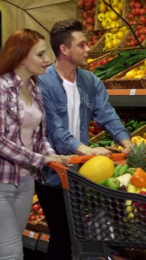 Neşeli genç bir çift çarşıda renkli taze sebzeleri zevkle keşfediyor. Işıl ışıl kızıl kız arabalarına gevrek bir lahana eklerken büyüleyici sarışın partneri neşe içinde...