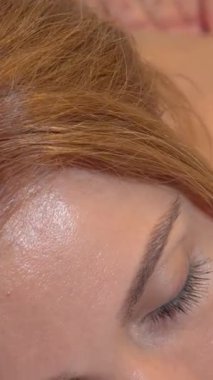 Huzurlu bir yakın plan, gözleri kapalı güzel bir kadını yakalar. Becerikli eller gençleştirici bir masaj yaparken yüzündeki saf mutluluğu yansıtır. Bu lüks spa deneyimi onu rahatlık ve sağlıkla kaplıyor, seni davet ediyor.