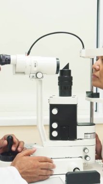 Parlak ve modern bir göz bilimi ofisinde, yetenekli bir doktor bir kadının gözlerini titizlikle son teknoloji bir aletle inceliyor. Bu samimi sahne doktorların odaklanma ve uzmanlık konusunda tereddütsüz bir şekilde kişisel gözün hayati önemini vurguladıklarını gösteriyor.