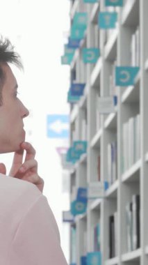 Yakışıklı genç bir adam modern bir kütüphanede duruyor, düşünceli bir şekilde organize kitap raflarına bakıyor, parmağı çenesinde dinleniyor. Parlak, sakin atmosfer onu canlı renkler ve vaatlerle dolu edebi bir yolculuğa davet ediyor.