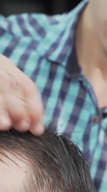 Kendini işine adamış bir kuaför erkek müşterisinin ıslak saçlarını titizlikle tarar, zarif bir berber dükkanında sanatını ve hassasiyetini gösterir. Parlak atmosfer profesyonelliği yansıtıyor, berberle berberin arasındaki yakın ilişkiyi vurguluyor.