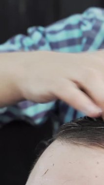 Kendini işine adamış bir kuaför şık bir berber dükkanında, erkek müşterisinin ıslak saçlarını ustalıkla tarar. Parlak atmosfer profesyonelliği yansıtıyor. Berberle müvekkil arasındaki yakın ilişkiyi gösteriyor.