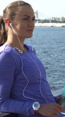 Uzun, siyah saçlı, at kuyruklu genç bir kadın trabzana yaslanıyor, pikoresk gibi nehir yürüyüşüne bakarken mp3 çalarda müziğinin tadını çıkarıyor. Canlı mor bir bluz giyer, elinde ferahlatıcı bir su şişesi ile mutluluk saçar.