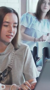 Şık gri bir bluz giyen neşeli genç bir kadın, hareketli bir kafede dumanı tüten bir fincan kahvenin tadını çıkarırken dizüstü bilgisayarına daldı. Çevrimiçi çalışmalarını tutkuyla sürdürürken, girişimci ruhu ortamı zenginleştiriyor.