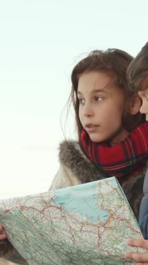 Geniş gözleri ve parlak gülümsemeleriyle, oğlan ve kız hevesle renkli haritalarını inceliyor, yüzleri keşfin heyecanıyla parlıyor. Kızın heyecanla işaret ettiği gibi, onların ifadeleri neşe ve merak yayar, ruhu somutlaştırır.