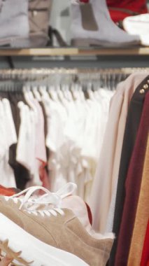 Kamerada dalgalı saçları olan, ışıl ışıl genç bir kadın şık kıyafetlerle dolu canlı bir perakende arkaplanının ortasında şık bir çift spor ayakkabı tutuyor. Bulaşıcı heyecanı, alışveriş çılgınlığının heyecanını yakalıyor.