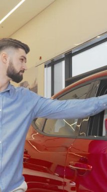 Gururlu bir adam, şık ve modern bir galeride göz alıcı yeni arabasının yanında dururken neşe saçıyor. Bu canlı sahne sahipliğin heyecanını özetliyor, arabaların parlaklığını vurguluyor, kendine güvenen gülümseme, başarıyı somutlaştırıyor ve