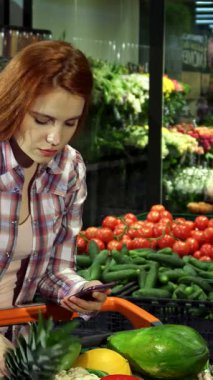 Çekici genç bir çift, canlı bir süpermarkette taze ürünlerin olduğu bir kaleydoskop içinde akıllı telefondan alışveriş listelerini kontrol ediyor. Yakışıklı sarışın adam, tatlı kızıl kız arkadaşını nazikçe kucaklıyor ve harika bir kız arkadaş yaratıyor.