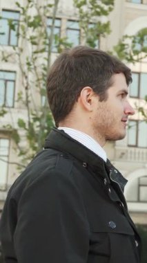 İki profesyonel erkek, biri açık tenli ve kısa saçlı, diğeri zeytin tenli, modern mimari ve verimli yeşilliklerle dolu canlı bir şehir zemininde kendinden emin bir tokalaşma paylaşıyorlar. Onların ciddi ifadeleri bir anlık...