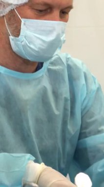 Gergin bir ameliyathanede, şefkatli bir hemşire cerrahın alnını nazikçe siler, sarsılmaz takım çalışmalarını ve konsantrasyonlarını vurgular. Bu samimi yakın plan çekimde steril mavi elbiseli iki erkek tıbbi uzman kendini tamamen...