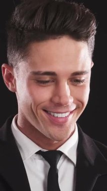 Gösterişli siyah takım elbiseli şık bir genç adam parlak gülüşüyle sıcaklığı yayar, sonra da izleyiciyi büyüleyen ciddi bakışlara geçişi kusursuz olur. Çarpıcı özellikleri, mükemmel şekillendirilmiş saçlar ve tanımlanmış kaşlar,