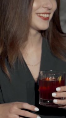 Dinamik bir çekim, canlı bir bar ortamında renkli kokteyl bardaklarını şakırdatan üç şık bayan arkadaşı yakalar. Hava kahkaha ve heyecanla dolu. Arkadaşlığı kutluyorlar ve canlı anılar yaratıyorlar.