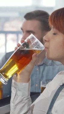 Lezzetli genç bir kadın, hareketli bir barda arkadaşlarıyla çevrili buzlu bir bardak altın zanaat birasını kaldırırken neşe saçıyor. Bu canlı sahne kutlama ve dostluğun ruhunu özetliyor, izleyicileri eğlence ve zevke davet ediyor.