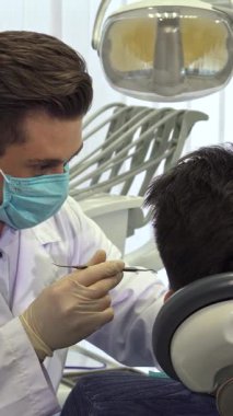 Gösterişli, çağdaş bir diş muayenehanesinde maske ve eldiven takmış genç sarışın bir dişçi müşterilerinin dişlerini dikkatle inceler. Elinde bir diş araştırmasıyla, profesyonelliği ve ilgiyi somutlaştıran yakından eğilir.