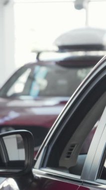 Sıcak bir gülümsemesi olan çekici bir adam parlak, modern bir bayilikte parlak, parlak bir arabaya yaslanır. Neşeli ifadesi, yeni bir araç seçmenin heyecanını yakalıyor, araba sahibi olmanın heyecanını ve önemli bir şey yapmanın sevincini simgeliyor.