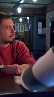 Bir barmen, parlak tezgahı ustalıkla siler ve cilalı cazibesini arttırır. Bu arada, hoş kırmızı kazaklı düşünceli genç beyaz bir adam bir spor oyununun heyecan verici atmosferine dalmış, birasının tadını çıkarıyor.