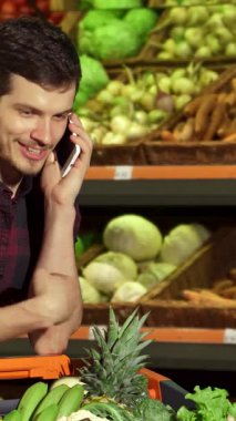 Şık, esmer bir adam alışveriş arabasının üzerine yaslanır ve canlı bir dizi taze ürünün arasında telefonda neşeyle sohbet eder. Onun ışıl ışıl gülüşü ve gevşek tavırları hareketli süpermarkete hayat veren bir enerji katıyor ve diğerlerini de bunu paylaşmaya davet ediyor.