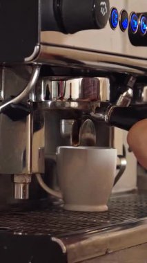 Tutkulu bir barista ustaca iki el değmemiş beyaz kupayı parlak bir espresso makinesinin altına yerleştirir ve aromatik kahveyi serbest bırakmaya hazırdır. Bu canlı kafe sahnesi insanı sarhoş eden taze fasulye kokusuna boğar.
