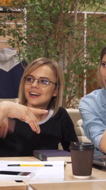 Canlı, genç, beyaz bir adam canlı bir çalışma alanındaki parlak bir dizüstü bilgisayarın etrafındaki kadın meslektaşlarıyla heyecan verici sezgilerini tutkuyla paylaşıyor. Gözlüklü şık esmer kadın hevesle eğilirken, büyüleyici kahverengi saçlı kadın çenesini dinlendiriyor.