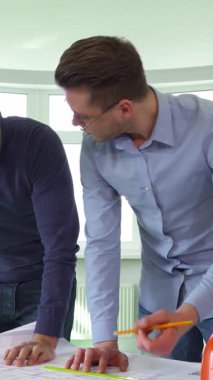 Doğal ışıkla dolu parlak, havadar bir ofiste, iki Kafkasyalı mimar bir inşaat projesinde heyecanlı bir işbirliğine giriştiler, yüzleri coşkuyla parlıyordu. Spor gözlüklü bir adam, mimari planları kalemle dikkatlice ölçüyor.